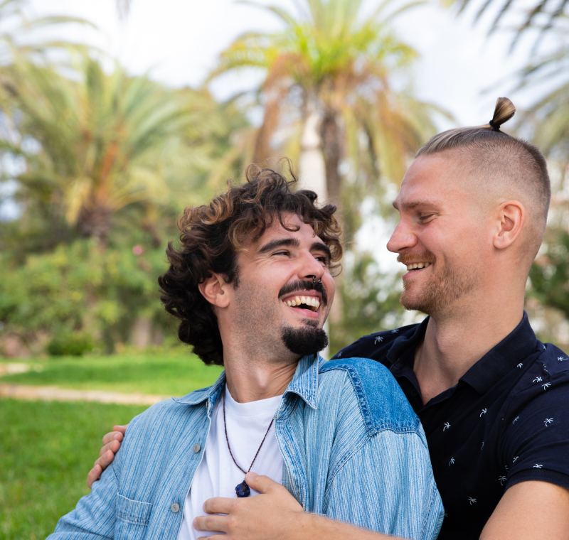 Couple d'hommes enlacés et rieurs dans un parc